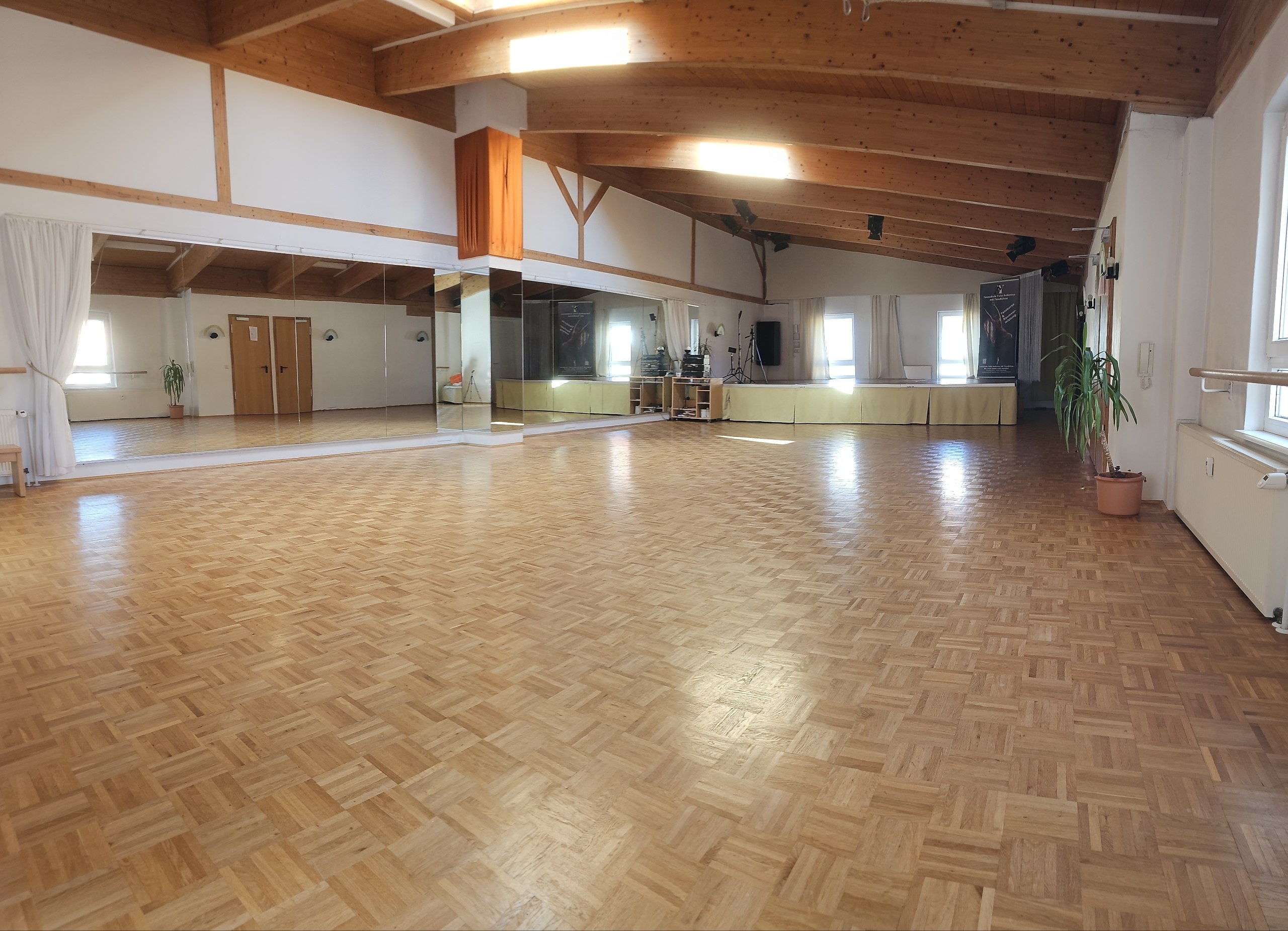 Leerer Tanzsaal mit glänzendem Parkett, Fensterfront und Bühne in Nürnberg